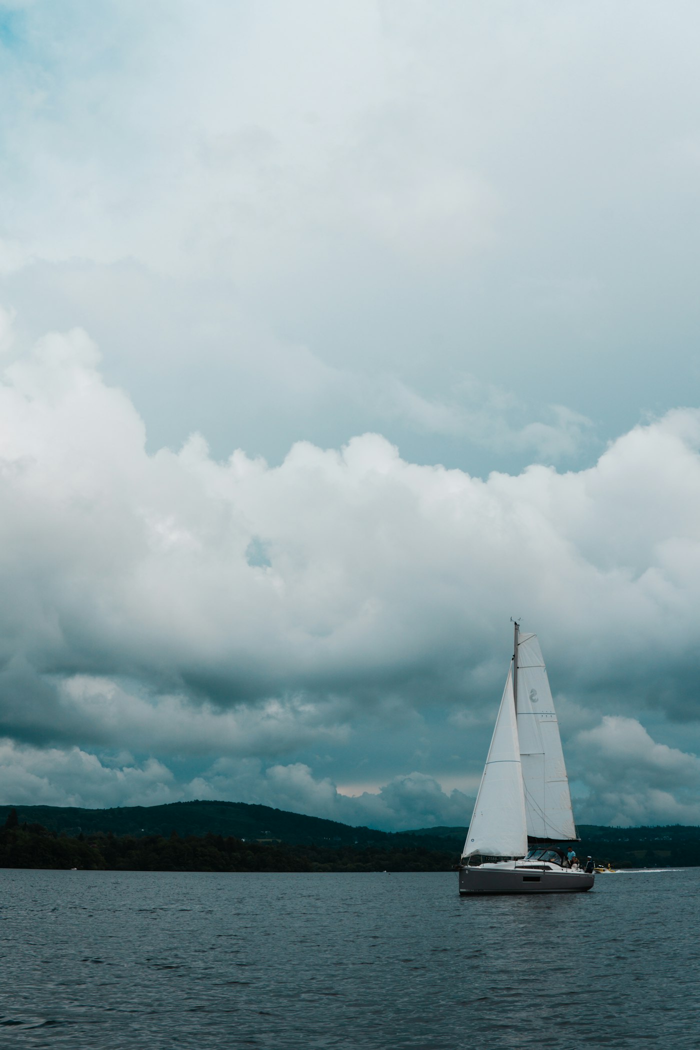 A sailing boat on Windermere beneath a dramatic sky